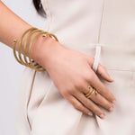 Zina Spiral Mesh Coil Bracelet by ARIIRA worn on wrist, showcasing a flexible gold design with polished end spheres.