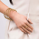 Zina Spiral Mesh Coil Bracelet by ARIIRA worn on wrist, showcasing a flexible gold design with polished end spheres.