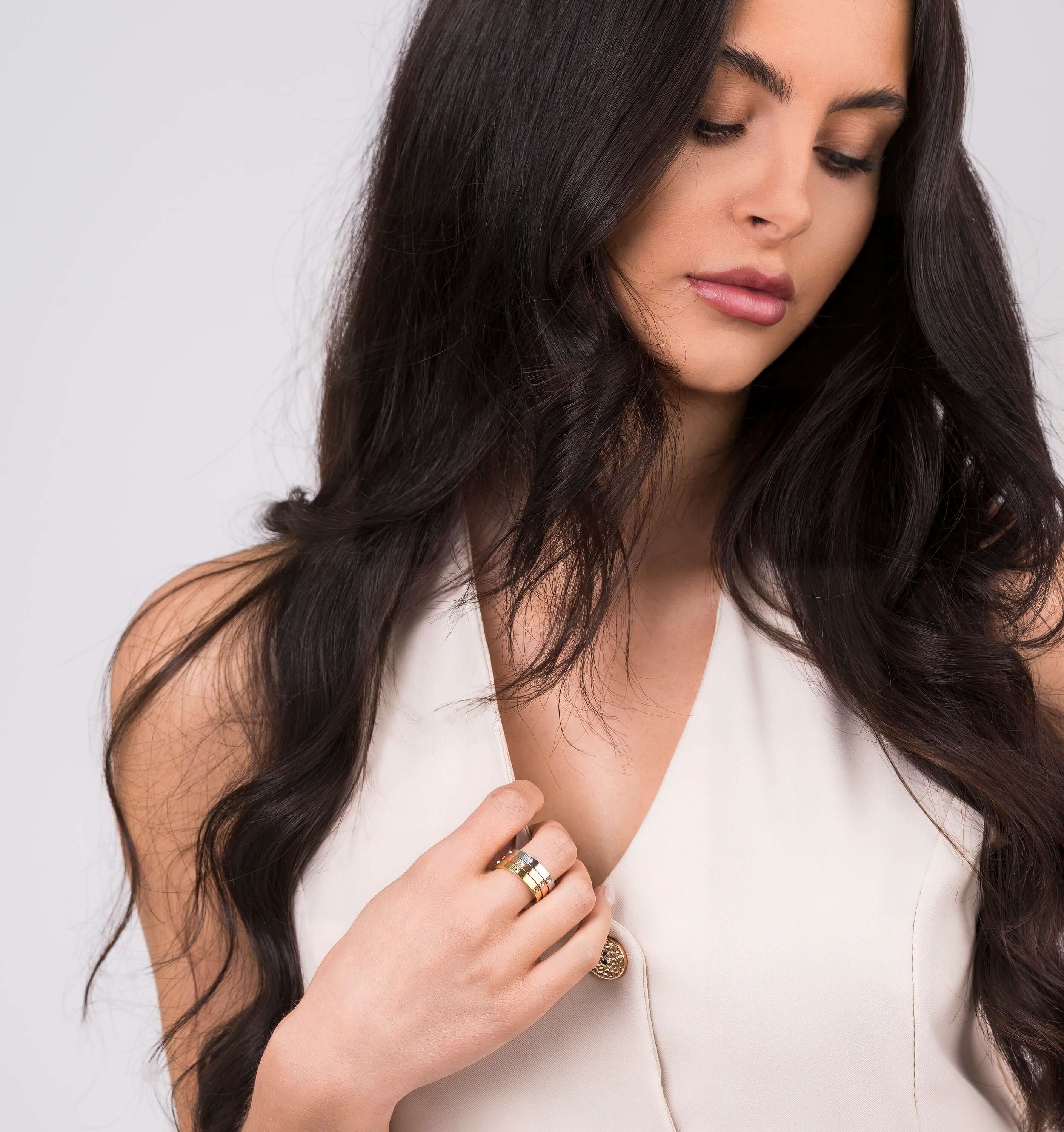 Woman wearing ARIIRA Kaia Triple Tone Crystal Ring Set featuring rose, gold, and silver bands with crystals.