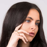 Model showcasing the ARIIRA Kaia Triple Tone Crystal Ring Set, featuring polished rose, gold, and silver bands.