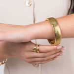 Close-up of Yasira Ribbed Wide Gold Bangle Bracelet and ring, showcasing modern jewelry design and elegance.