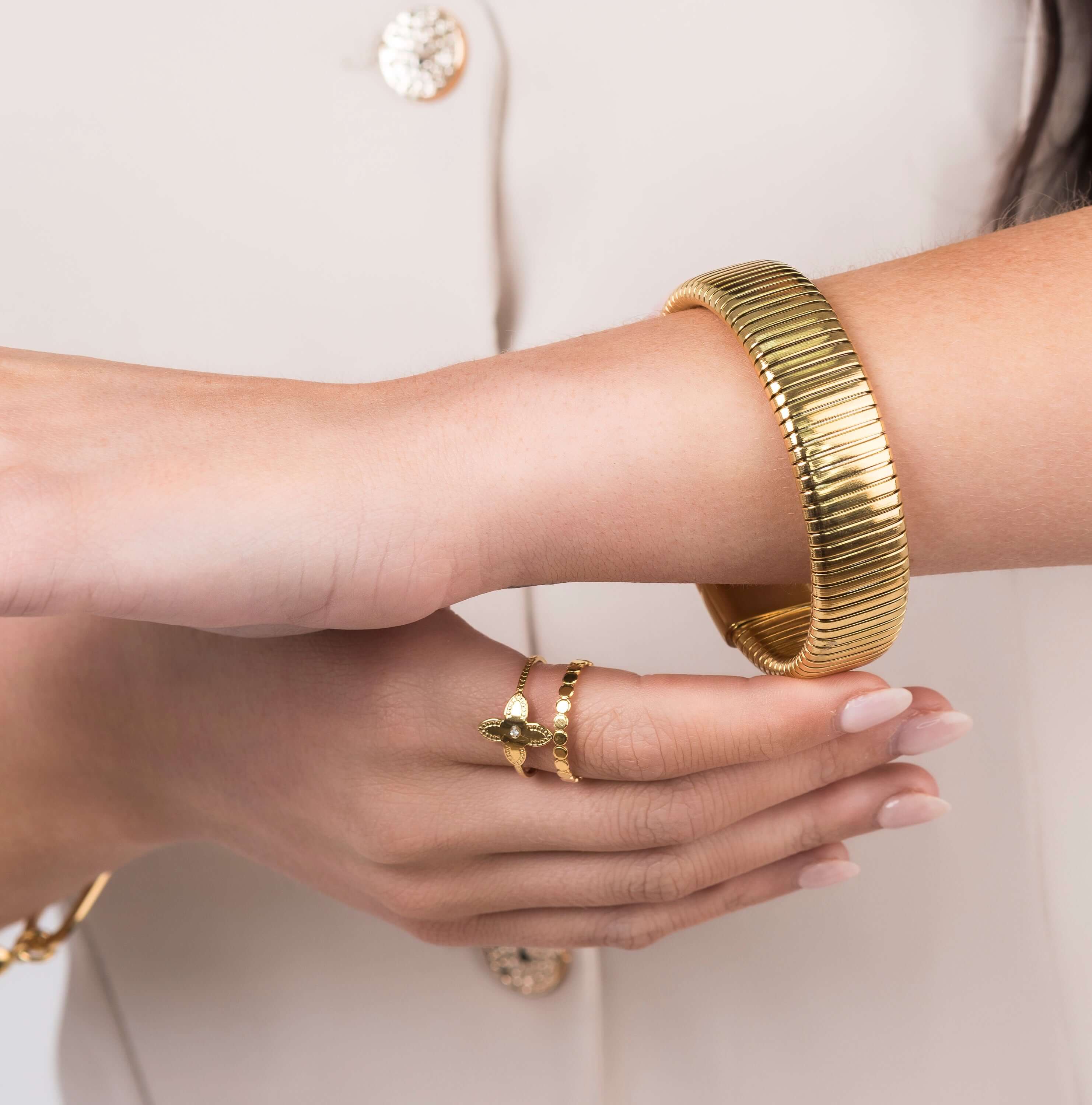 Close-up of Yasira Ribbed Wide Gold Bangle Bracelet and ring, showcasing modern jewelry design and elegance.