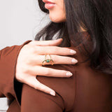 Close-up of a woman wearing an adjustable Lyra green stone open ring by ARIIRA, showcasing its modern gold design.