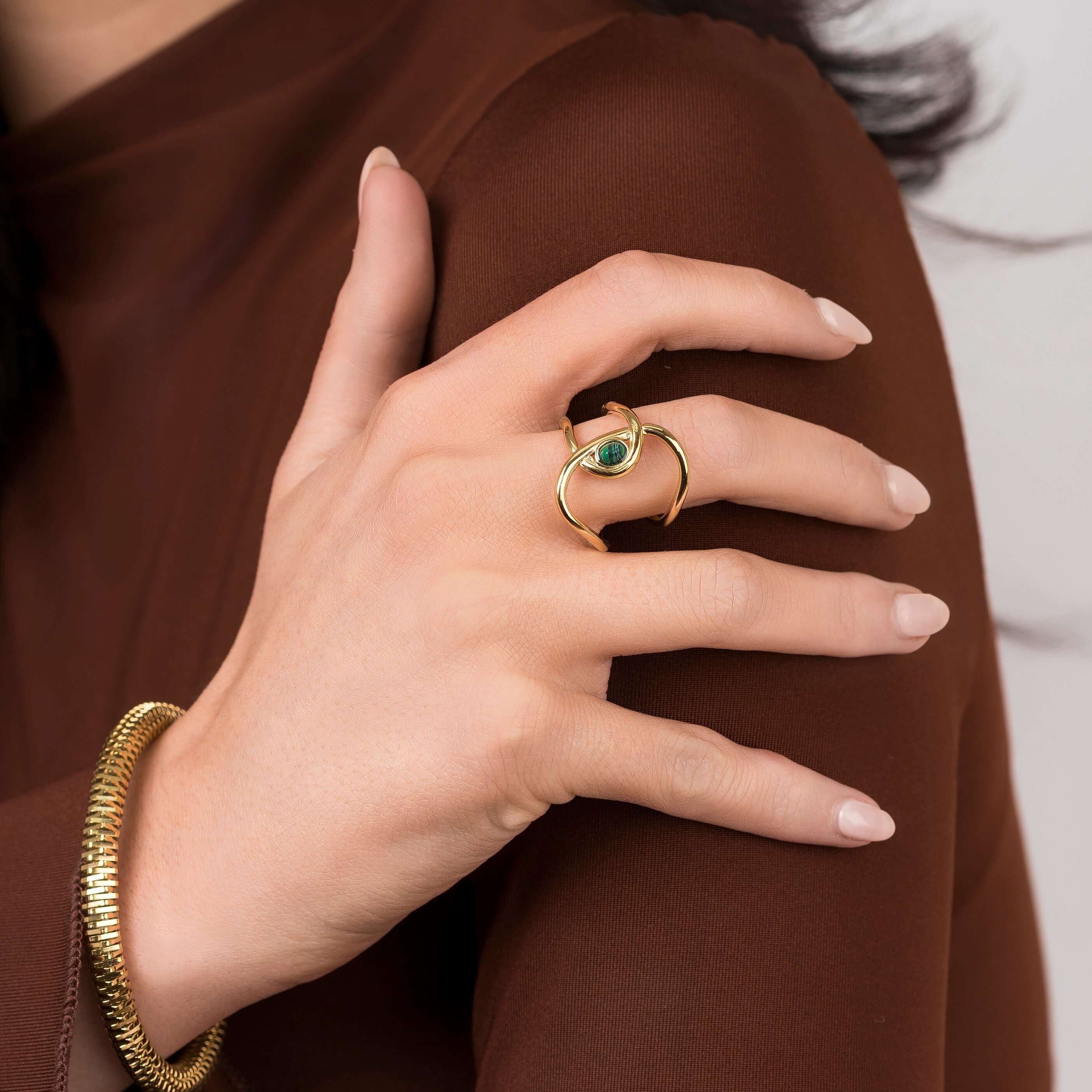 Close-up of a hand wearing the ARIIRA Lyra Green Stone Open Ring, featuring a gold design and deep green stone.