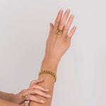 Stylish woman showcasing Raisa Sculpted Link Bracelet with crystal insets and matching gold rings.