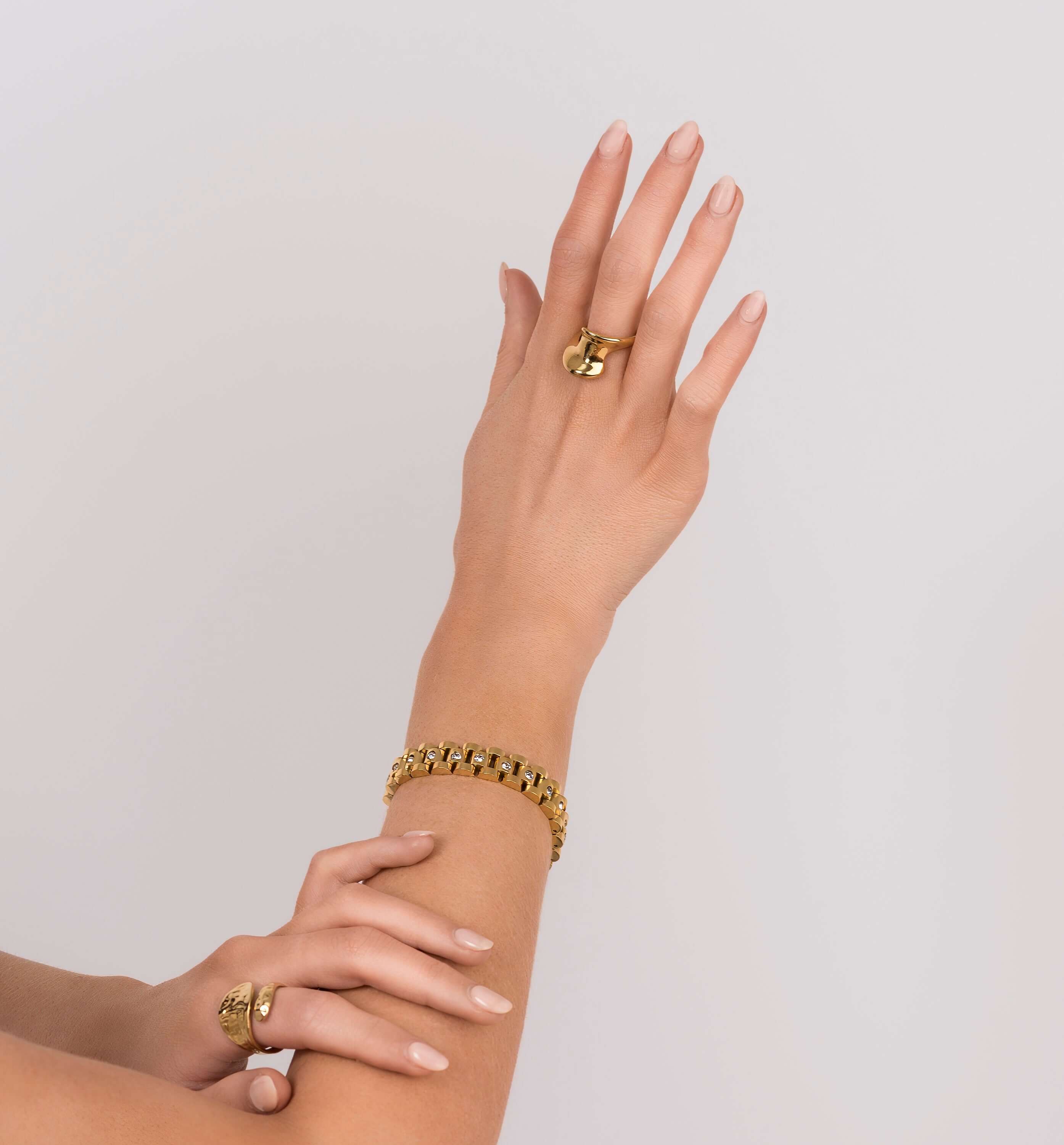 Stylish woman showcasing Raisa Sculpted Link Bracelet with crystal insets and matching gold rings.