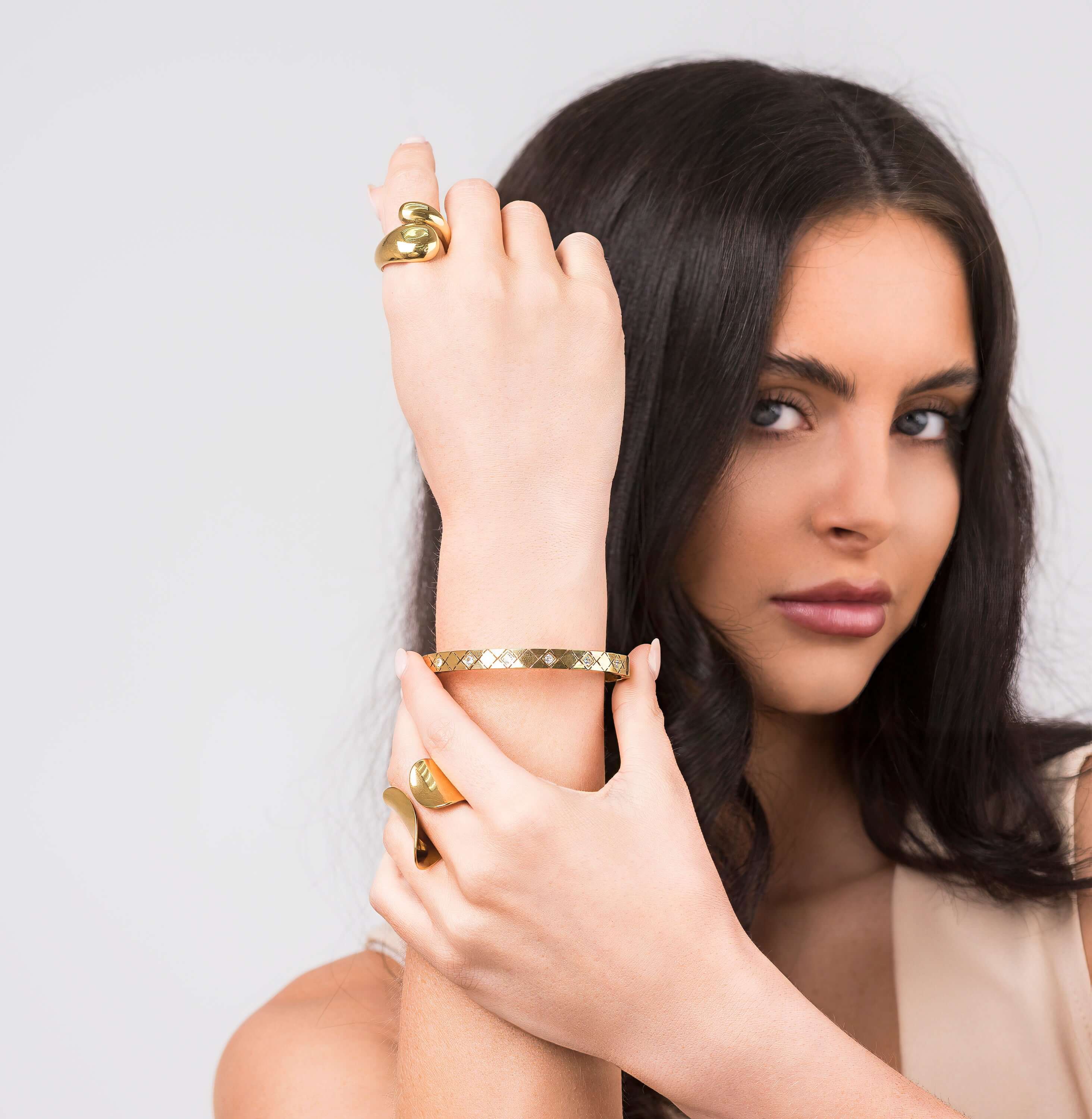 Close-up of a woman wearing the Ameera Lattice Engraved Gold Bangle Bracelet, showcasing its crisscross engraving and elegant design.