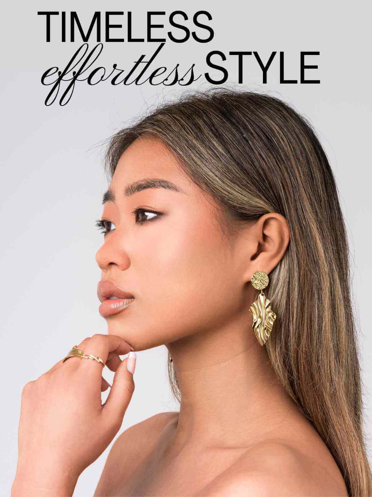 A woman showcases timeless and effortless style with elegant gold earrings and a chic hairstyle.